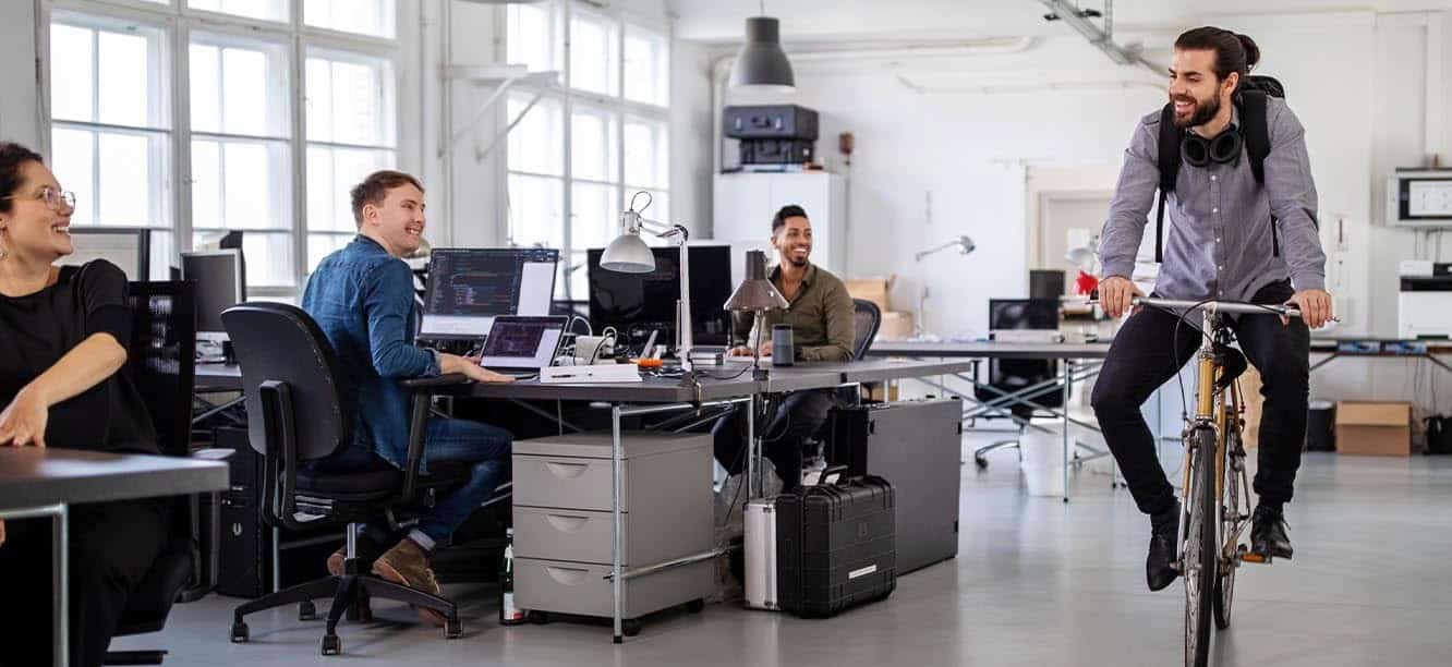 Creative professionals in office looking for creative jobs in Atlanta; man on bicycle riding through office