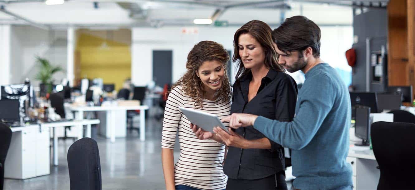 Three marketing professionals looking at tablet for creative jobs in Denver, CO