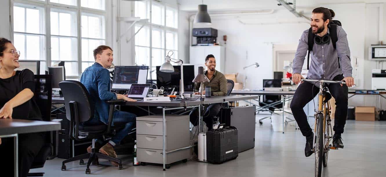 Creative professionals in office looking for creative jobs in San Francisco; man on bicycle riding through office